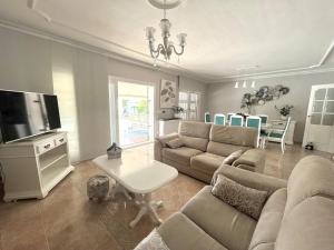 Una sala de estar con un sofá y un televisor de pantalla plana. en Villa de lujo al lado del mar, piscina, garaje wifi, AACC, en Alicante