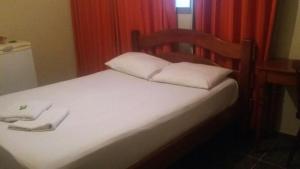 a bed with two white pillows on top of it at Hotel Dois Candangos in Brasília