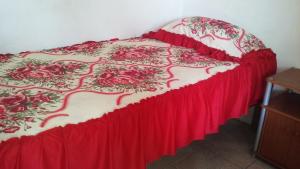 a bed with a red and white comforter on it at Cabinas Smith 2 in Cahuita