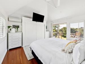 ヤンバにあるVilla Kalinya! Beachside Treehouse Oasisの白いベッドルーム(ベッド1台、テレビ付)