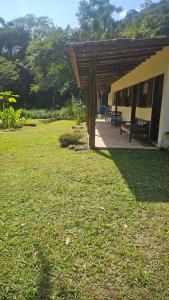 a house with a wooden roof and a grass yard at Recanto da Mata in Paraty