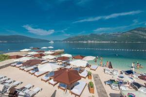 a beach with chairs and umbrellas and people in the water at Apartment MilaS in Tivat
