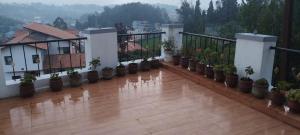 Elle comprend un balcon avec des plantes en pot et du parquet. dans l'établissement Chill view cottage, à Ooty