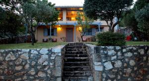 a house with a stone wall and stairs in front at Il Suo Paradiso in Dhavgáta