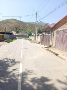 an empty street in a town with mountains in the background at Гостевой дом in Naryn +6 photos