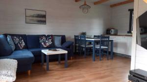 a living room with a blue couch and a table at Domek nad rzeką in Borsk