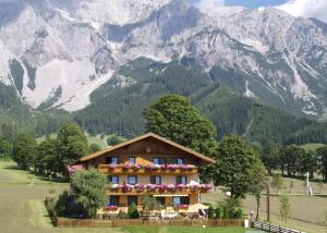 ein Haus auf einem Feld mit Bergen im Hintergrund in der Unterkunft Ferienwohnung Alpenecho in Ramsau am Dachstein