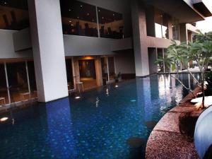 a large swimming pool in a building with blue water at Arch Hotel Bogor in Bogor