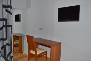 a desk with a chair and a television on a wall at Hotel Jarama in Zamora