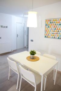 a white dining room table with white chairs and a potted plant at Apto. Santa Susanna in Santa Susanna