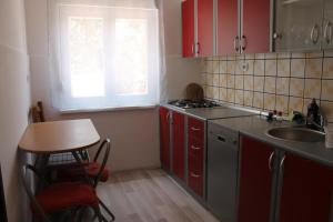 a kitchen with red cabinets and a sink and a window at Apartment Ruby in Mandre