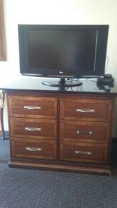 a television on top of a wooden dresser at Cedars Inn Lewiston in Lewiston