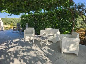 a group of white chairs and tables on a patio at Villa Paola Pantalica in Cassaro