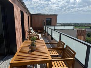 a balcony with wooden tables and chairs on a building at Appartement Le Riva B304 in Barneville-Carteret