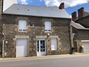 un antiguo edificio de ladrillo con tres puertas blancas de garaje en Gîte le Laurier, en Saint-James