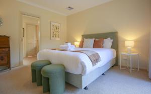 a bedroom with a large bed with two ottomans and a bedsenal at On The Trail in Bright