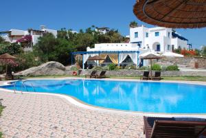 a swimming pool with chairs and a building in the background at Koulas Pension - Red Lake in Agios Prokopios