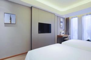 a hotel room with a bed and a tv on a wall at Yitel Collection Harbin Railway Station Museum Metro Station in Harbin