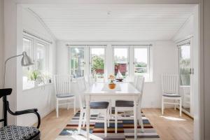 a white dining room with a white table and chairs at Charmig Villa bredvid sjön Örlen in Tibro