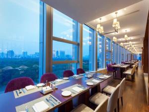 un ristorante con tavoli e sedie e grandi finestre di Ming Du Lakeside Hotel Nanning a Nanning Altre 237 foto