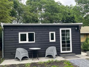 a black tiny house with two chairs and a table at Zwart Pareltje in Kiel