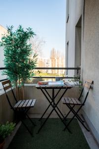 ein Tisch und zwei Stühle auf einem Balkon mit einem Baum in der Unterkunft Chaleureux T3 aux pieds du Stade de France in Saint-Denis