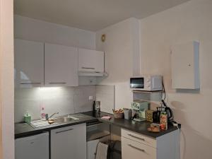 a small kitchen with white cabinets and a sink at le classique in Besançon