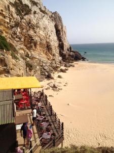 uma praia com cadeiras e pessoas na areia em Beach front apartment 1 em Sagres