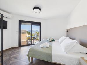 a white bedroom with a bed and a balcony at Résidence Aigue Marine in Coti-Chiavari