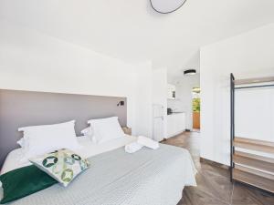 een slaapkamer met een wit bed en een groen kussen bij Résidence Aigue Marine in Coti-Chiavari