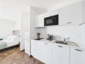 a white kitchen with a sink and a microwave at Résidence Aigue Marine in Coti-Chiavari