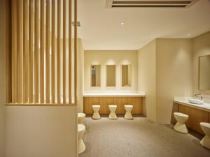 a bathroom with a row of toilets and a sink at Mitsui Garden Hotel Kyoto Shijo in Kyoto