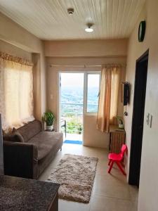 un salon avec un canapé et une grande fenêtre dans l'établissement Mountain and City View 1Bedroom Condo, à Baguio 9 autres photos