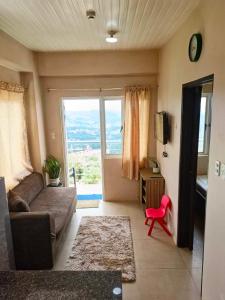 un salon avec un canapé et une grande fenêtre dans l'établissement Mountain and City View 1Bedroom Condo, à Baguio