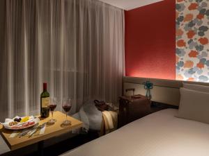 a hotel room with a bed and a table with wine glasses at Mitsui Garden Hotel Kyoto Shijo in Kyoto
