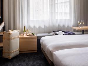 a hotel room with two beds and a table with wine glasses at Mitsui Garden Hotel Kyoto Shijo in Kyoto