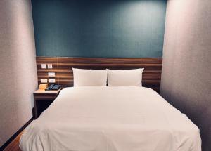 a bedroom with a large white bed with a blue wall at Tomorrow Hotel in Taipei