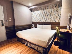 a bedroom with a large white bed and a desk at Tomorrow Hotel in Taipei
