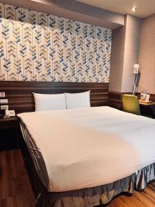 a bedroom with a large white bed and a chair at Tomorrow Hotel in Taipei