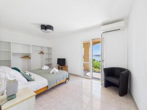 een slaapkamer met een bed, een stoel en een raam bij Résidence Aigue Marine in Coti-Chiavari