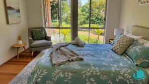 a bedroom with a bed and a chair and a window at Balcolyns Beauty - the ultimate lakeside escape in Eraring