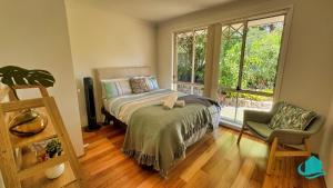 a bedroom with a bed and a window and a chair at Balcolyns Beauty - the ultimate lakeside escape in Eraring +16 photos