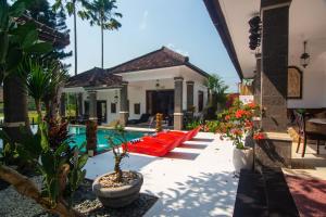 a house with a pool with red pillows and plants at Balam Bali Villa in Mengwi