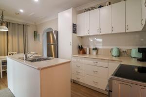 a kitchen with white cabinets and a stainless steel refrigerator at Beachside Cottage at Blacksmiths in Blacksmiths +18 photos