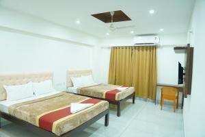 una habitación de hotel con dos camas y una silla en Kukkeshree Heights, en Subrahmanya 20 fotos más