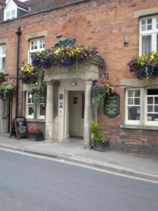 un bâtiment avec des boîtes de fleurs à l'avant dans l'établissement The Green Dragon, à Market Lavington