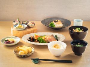 a table with bowls and plates of food on it at Mitsui Garden Hotel Kyoto Shijo in Kyoto