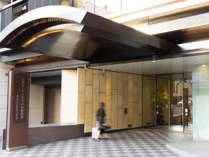 a person walking in front of a building at Mitsui Garden Hotel Kyoto Shijo in Kyoto