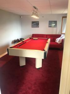 a pool table in a living room with a red couch at Chalet de la Roche Gauthier in Gérardmer