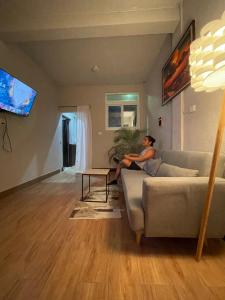 a woman sitting on a couch in a living room at Residencia Boho in San Pedro La Laguna